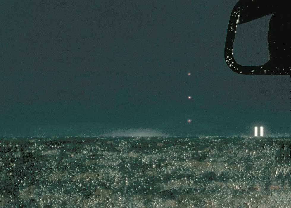 View from the driver's seat of a car, with strange-looking lights in the sky-- here focusing on the distant lights on right horizon