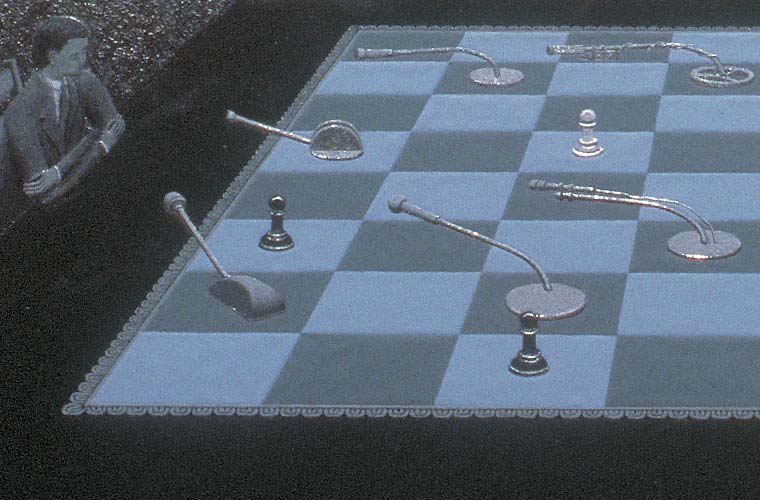 Detail of nightscape with figure seated next to a table on which is a chessboard containing a mixture of microphones and pawns, here focusing on the seated man, microphones, and pawns